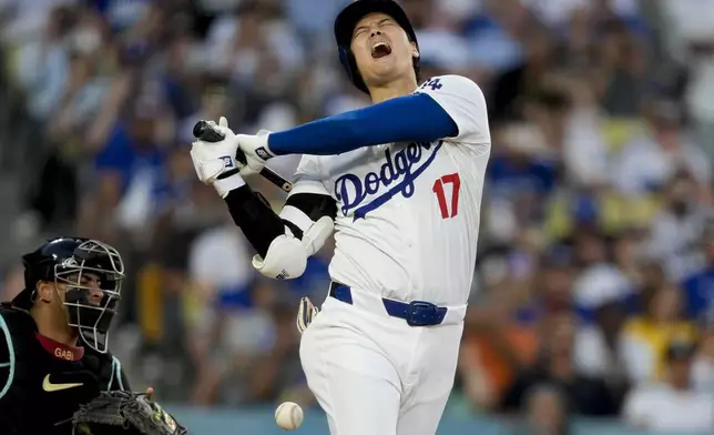 Los Angeles Dodgers designated hitter Shohei Ohtani reacts after being hit by a foul tip during the third inning of a baseball game against the Arizona Diamondbacks, Tuesday, July 2, 2024, in Los Angeles. (AP Photo/Ryan Sun)