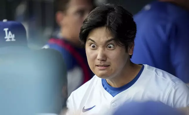 Los Angeles Dodgers designated hitter Shohei Ohtani interacts with teammates in the dugout before a baseball game against Philadelphia Phillies in Los Angeles, Wednesday, Aug. 7, 2024. (AP Photo/Eric Thayer)