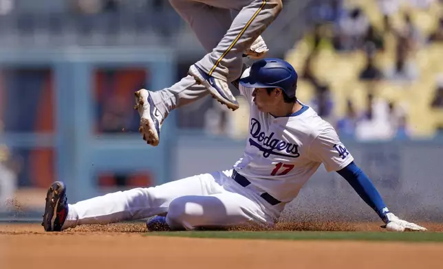 Los Angeles Dodgers' Shohei Ohtani, below, slides into second in an attempt to steal as Milwaukee Brewers second baseman Brice Turang jumps over him during the third inning of a baseball game Sunday, July 7, 2024, in Los Angeles. (AP Photo/Mark J. Terrill)