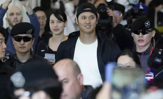 Los Angeles Dodgers Shohei Ohtani, center, walks with his wife Mamiko Tanaka, center left, through a terminal during the baseball team's arrival at Incheon International Airport, Friday, March 15, 2024, in Incheon, South Korea, ahead of the team's baseball series against the San Diego Padres. (AP Photo/Ahn Young-joon)