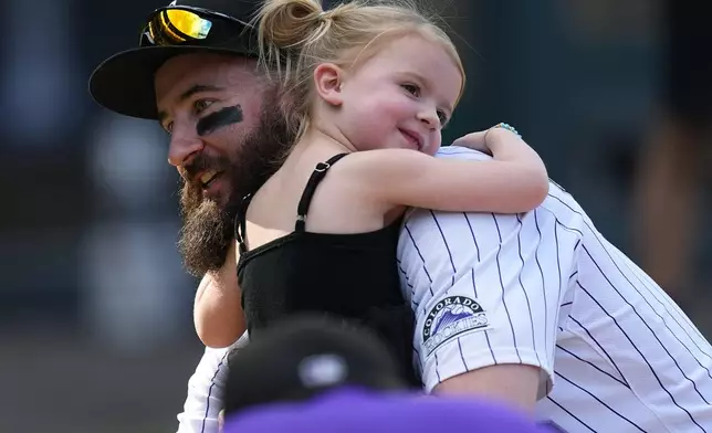 Retiring Colorado Rockies outfielder Charlie Blackmon, left, is hugged by his 3-year-old daughter Josie, right, during the team's ceremonial walk around the field to acknowledge fans following a baseball game loss to the Los Angeles Dodgers, Sunday, Sept. 29, 2024, in Denver. (AP Photo/David Zalubowski)