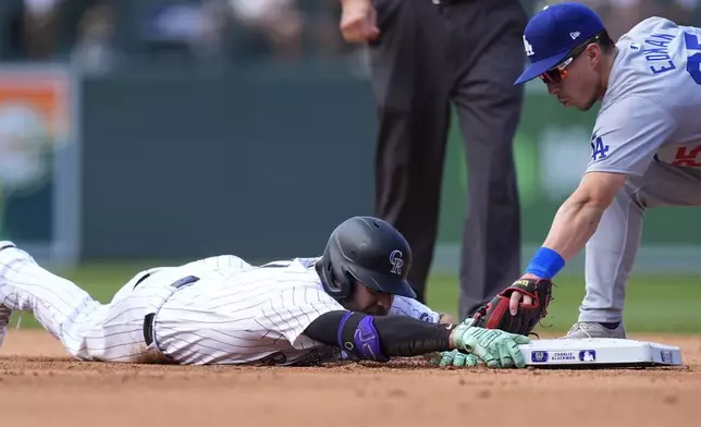 Colorado Rockies' Jake Cave, left, slides safely into second base with a double as Los Angeles Dodgers shortstop Tommy Edman, right, applies a late tag in the fifth inning of a baseball game Sunday, Sept. 29, 2024, in Denver. (AP Photo/David Zalubowski)