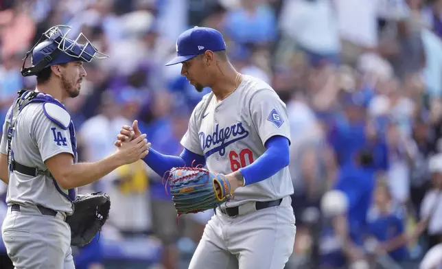 Los Angeles Dodgers catcher Austin Barnes, left, congratulates relief pitcher Edgardo Henriquez after defeting the Colorado Rockies in a baseball game Sunday, Sept. 29, 2024, in Denver. (AP Photo/David Zalubowski)