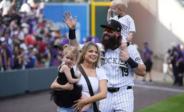 Retiring Colorado Rockies outfielder Charlie Blackmon, right, thanks fans alongside wife Ashley and children Josie and Wyatt during the team's ceremonial walk around the field following a loss in the season finale, Sunday, Sept. 29, 2024, in Denver. (AP Photo/David Zalubowski)