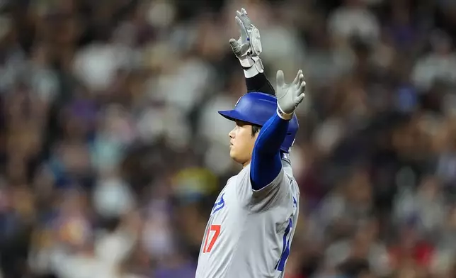 Los Angeles Dodgers' Shohei Ohtani gestures to the dugout after reaching second base on a double off Colorado Rockies relief pitcher Luis Peralta in the eighth inning of a baseball game, Friday, Sept. 27, 2024, in Denver. (AP Photo/David Zalubowski)