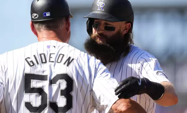 Colorado Rockies' Charlie Blackmon, right, hugs first base coach Ronnie Gideon (53) after hitting a single in his final at-bat in the third inning of a baseball game againstt he Los Angeles Dodgers, Sunday, Sept. 29, 2024, in Denver. (AP Photo/David Zalubowski)