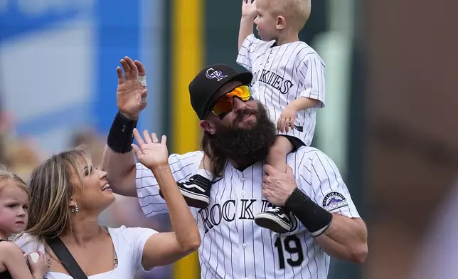 Colorado Rockies' Charlie Blackmon, third from left, carries his 2-year-old son, Wyatt, while walking with his wife, Ashley, and 3-year-old daughter, Josie, during the team's ceremonial walk around the field to acknowledge fans following a loss in the team's season finale, Sunday, Sept. 29, 2024, in Denver. (AP Photo/David Zalubowski)