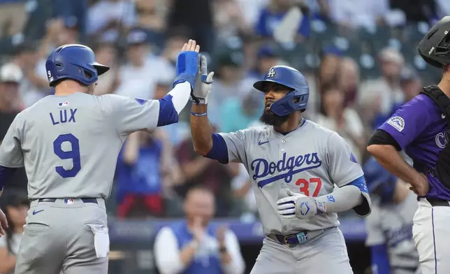 Los Angeles Dodgers' Gavin Lux, left, congratulates Teoscar Hernández as he crosses home plate after hitting a two-run home run off Colorado Rockies starting pitcher Cal Quantrill in the first inning of a baseball game, Friday, Sept. 27, 2024, in Denver. (AP Photo/David Zalubowski)