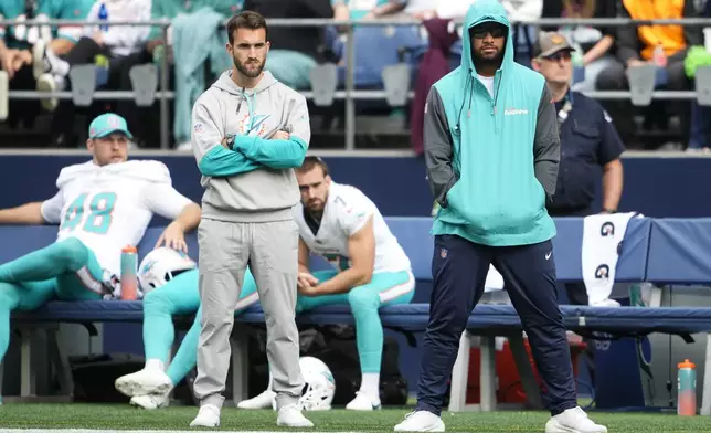 Miami Dolphins quarterback Tua Tagovailoa, right, looks on from the sideline during the first half of an NFL football game against the Seattle Seahawks, Sunday, Sept. 22, 2024, in Seattle. (AP Photo/Lindsey Wasson)