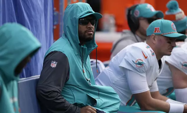 Miami Dolphins quarterback Tua Tagovailoa, center, looks on from the sideline during the first half of an NFL football game against the Seattle Seahawks, Sunday, Sept. 22, 2024, in Seattle. (AP Photo/Stephen Brashear)