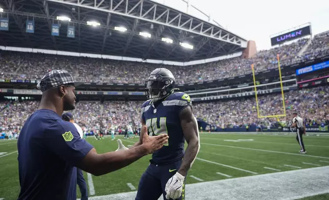 Seattle Seahawks wide receiver DK Metcalf (14) greets running back Kenneth Walker III after scoring a touchdown during the first half of an NFL football game against the Miami Dolphins, Sunday, Sept. 22, 2024, in Seattle. (AP Photo/Lindsey Wasson)