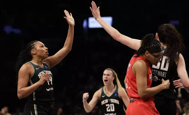 New York Liberty forward Betnijah Laney-Hamilton (44) high-fives Breanna Stewart, right, as Liberty guard Sabrina Ionescu (20) looks on while Atlanta Dream guard Allisha Gray ducks away during the first half of a first-round WNBA basketball playoff game, Tuesday, Sept. 24, 2024, in New York. (AP Photo/Adam Hunger)