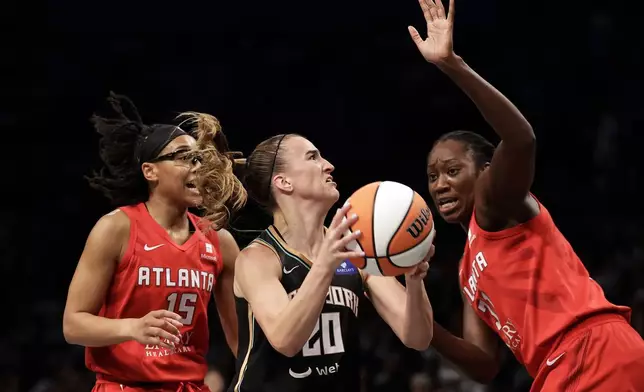 New York Liberty guard Sabrina Ionescu (20) drives to the basket between Atlanta Dream guard Allisha Gray (15) and Tina Charles during the first half of a first-round WNBA basketball playoff game, Tuesday, Sept. 24, 2024, in New York. (AP Photo/Adam Hunger)