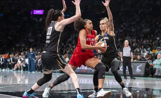 Atlanta Dream guard Haley Jones (13) drives between New York Liberty forwards Breanna Stewart (30) and Leonie Fiebich, front right, during the second half of a WNBA basketball first-round playoff game Sunday, Sept. 22, 2024, in New York. (AP Photo/Corey Sipkin)