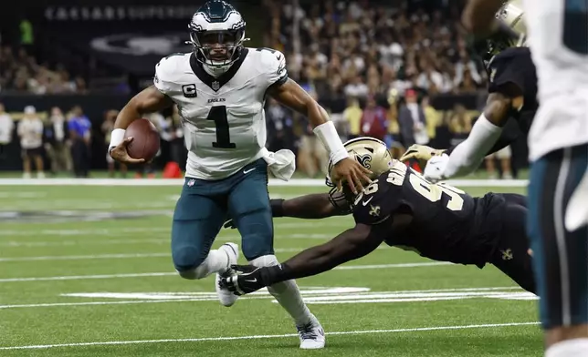 Philadelphia Eagles quarterback Jalen Hurts (1) scrambles past New Orleans Saints defensive end Carl Granderson (96) in the first half of an NFL football game in New Orleans, Sunday, Sept. 22, 2024. (AP Photo/Butch Dill)