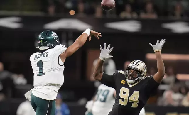 Philadelphia Eagles quarterback Jalen Hurts (1) passes over the reach of New Orleans Saints defensive end Cameron Jordan (94) in the second half of an NFL football game in New Orleans, Sunday, Sept. 22, 2024. (AP Photo/Gerald Herbert)