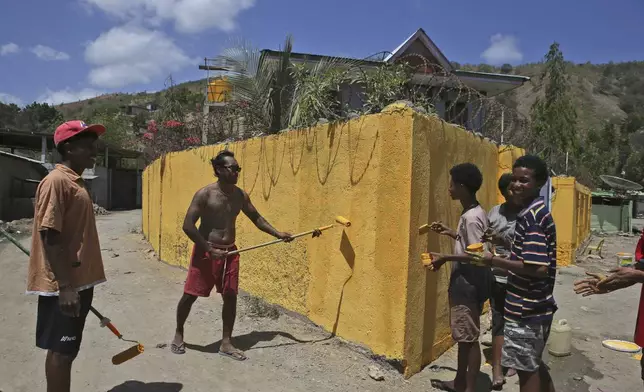 People paint the wall of a house in Dili, East Timor, Friday, Sept. 6, 2024. (AP Photo/Firdia Lisnawati)