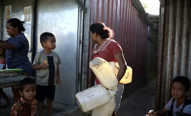 A woman carries plastic cans to buy water at a market in Dili, East Timor on Friday, Sept. 6, 2024. (AP Photo/Firdia Lisnawati)