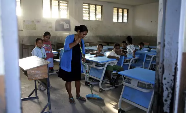 A school teacher sweeps the floor of a classroom before the start of classes in Dili, East Timor, Thursday, Sept. 5, 2024. (AP Photo/Firdia Lisnawati)