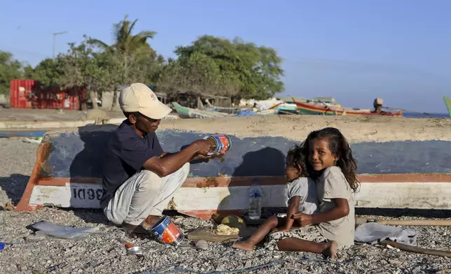 A fisherman repairs his boat, with his daughters sitting beside him at a beach in Dili, East Timor, Friday, Sept. 6, 2024. (AP Photo/Firdia Lisnawati)