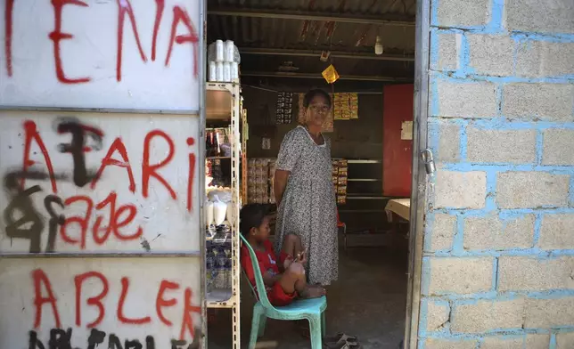 Ana Darojo stands inside her shop with her son in Dili, East Timor, Friday, Sept. 6, 2024. (AP Photo/Firdia Lisnawati)