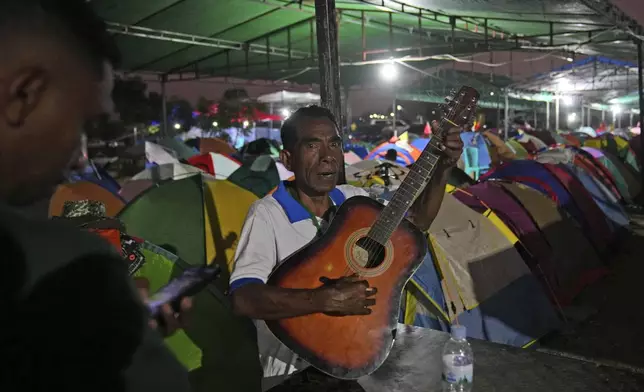 Mariano Soares who came from Oecusse, about 200 kilometers (124 miles) from the capital of Dili, plays a guitar near a row of tents belonging to people who camp for days while waiting to attend the holy mass presided by Pope Francis on Sept. 10, in Dili, East Timor, Sunday, Sept. 8, 2024. (AP Photo/Dita Alangkara)