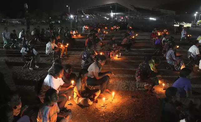 People who came from Oecusse, about 200 kilometers (124 miles) from the capital of Dili, light candles during an evening mass on the field where they camp while waiting to attend the holy mass presided by Pope Francis scheduled on Sept. 10, in Dili, East Timor, Sunday, Sept. 8, 2024. (AP Photo/Dita Alangkara)