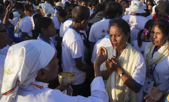 Faithful receive communion during the holy mass lead by Pope Francis at Tasitolu park in Dili, East Timor, Tuesday, Sept. 10, 2024. (AP Photo/Dita Alangkara, Pool)