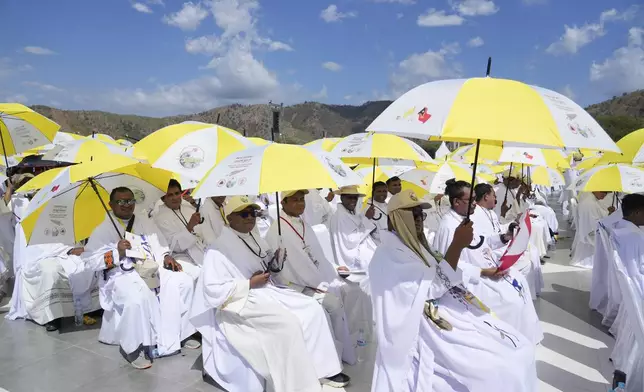 Faithful and priests use umbrellas with the colors of the Vatican flag to shield themselves from the sun as they wait for a mass presided over by Pope Francis to start in Tasitolu, some 8 kilometers west of Dili, East Timor, Tuesday, Sept. 10, 2024. Pope Francis presides over a mass in a seaside park on the same field where St. John Paul II celebrated a historic liturgy during East Timor's fight for independence from Indonesian rule. (AP Photo/Gregorio Borgia)