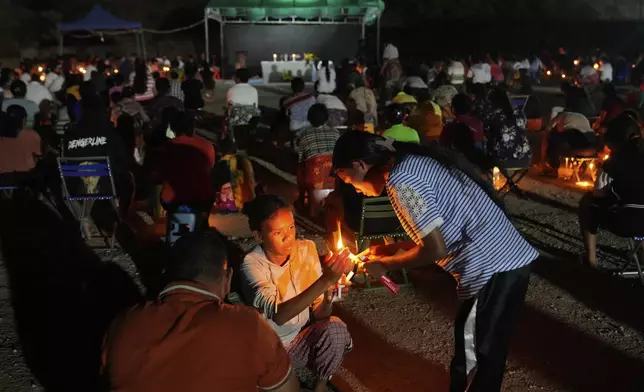 People who came from Oecusse, about 200 kilometers (124 miles) from the capital of Dili, light candles during an evening mass on the field where they camp while waiting to attend the holy mass presided by Pope Francis scheduled on Sept. 10, in Dili, East Timor, Sunday, Sept. 8, 2024. (AP Photo/Dita Alangkara)