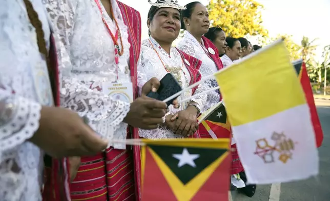 Faithful in traditional dress singing and chanting on the side of the road outside the airport as they prepare to bid farewell to Pope Francis in Dili, East Timor, Wednesday, Sept. 11, 2024. (AP Photo/Dita Alangkara)