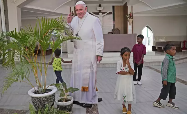 Children play near a cutout of Pope Francis installed at a church ahead of his visit to East Timor, in Dili, Sunday, Sept. 8, 2024. (AP Photo/Dita Alangkara)