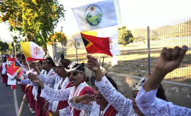 Faithful in traditional dress singing and chanting on the side of the road outside the airport as they prepare to bid farewell to Pope Francis in Dili, East Timor, Wednesday, Sept. 11, 2024. (AP Photo/Dita Alangkara)