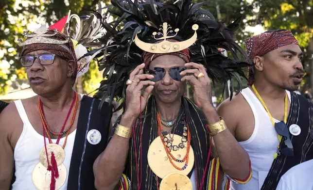 Men and women in traditional dress singing and chanting on the side of the road outside the airport as they prepare to bid farewell to Pope Francis in Dili, East Timor, Wednesday, Sept. 11, 2024. (AP Photo/Dita Alangkara)