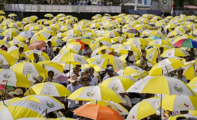 Faithful use umbrellas with the colors of the Vatican flag to shield themselves from the sun as they wait for a mass presided over by Pope Francis to start in Tacitolu, some 8 kilometers west of Dili, East Timor, Tuesday, Sept. 10, 2024. Pope Francis presides over a mass in a seaside park on the same field where St. John Paul II celebrated an historic liturgy during East Timor's fight for independence from Indonesian rule. (AP Photo/Gregorio Borgia)