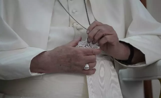 Pope Francis holds his cross pendant during a visit at the 'Irmas ALMA' (Sisters of the Association of Lay Missionaries) School for Children with Disabilities in Dili, East Timor, Tuesday, Sept. 10, 2024. Pope Francis has indirectly acknowledged the abuse scandal in East Timor involving its Nobel Peace Prize-winning independence hero Bishop Carlos Filipe Ximenes Belo. (AP Photo/Gregorio Borgia)