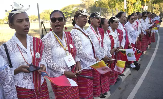 Faithful in traditional dress singing and chanting on the side of the road outside the airport as they prepare to bid farewell to Pope Francis in Dili, East Timor, Wednesday, Sept. 11, 2024. (AP Photo/Dita Alangkara)