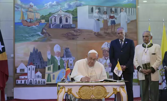 Pope Francis signs a guestbook as East Timor's President Jose Ramos-Horta, right, looks on at the Presidential Palace in Dili, East Timor, Monday, Sept. 9, 2024. (Tiziana Fabi/Pool Photo via AP)