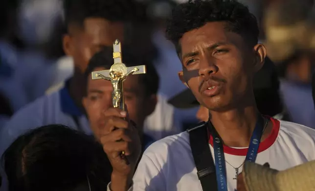 A catholic faithful holds a cross during the holy mass lead by Pope Francis at Tasitolu park in Dili, East Timor, Tuesday, Sept. 10, 2024. (AP Photo/Dita Alangkara, Pool)