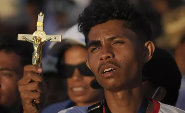 A catholic faithful holds a cross during the holy mass lead by Pope Francis at Tasitolu park in Dili, East Timor, Tuesday, Sept. 10, 2024. (AP Photo/Dita Alangkara, Pool)