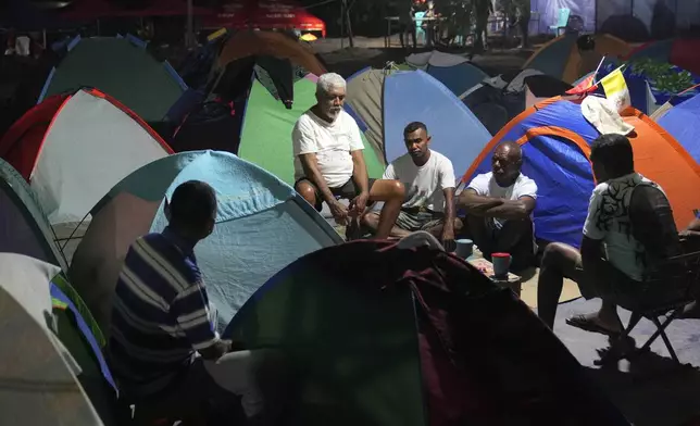 Venansio Lafo, center, who came from Oecusse, about 200 kilometers (124 miles) from the capital of Dili, talks with friends outside the tents where they camp for days while waiting to attend the holy mass presided by Pope Francis scheduled on Sept. 10, in Dili, East Timor, Sunday, Sept. 8, 2024. (AP Photo/Dita Alangkara)