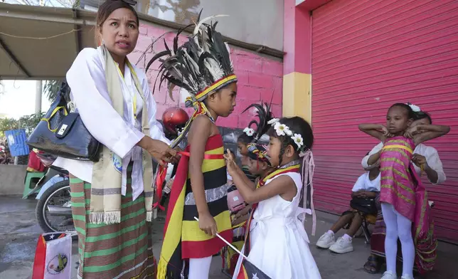 A mother helps her son to wear a traditional outfit to welcome Pope Francis' visit in Dili, East Timor Monday, Sept. 9, 2024. (AP Photo/Firdia Lisnawati)