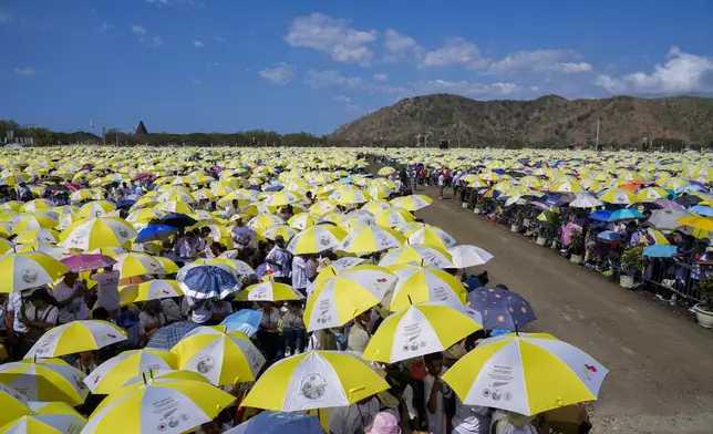 Faithful use umbrellas with the colors of the Vatican flag to shield themselves from the sun as they wait for a mass presided over by Pope Francis to start in Tasitolu, some 8 kilometers west of Dili, East Timor, Tuesday, Sept. 10, 2024. Pope Francis presides over a mass in a seaside park on the same field where St. John Paul II celebrated a historic liturgy during East Timor's fight for independence from Indonesian rule. (AP Photo/Gregorio Borgia)