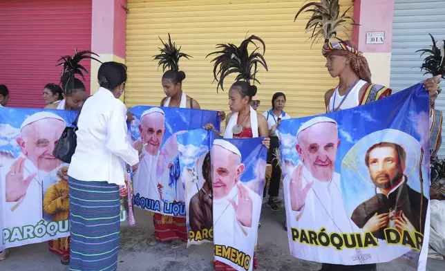 People with traditional dress hold banners of Pope Francis as they prepare to welcome the pope's visit in Dili, East Timor Monday, Sept. 9, 2024. (AP Photo/Firdia Lisnawati)