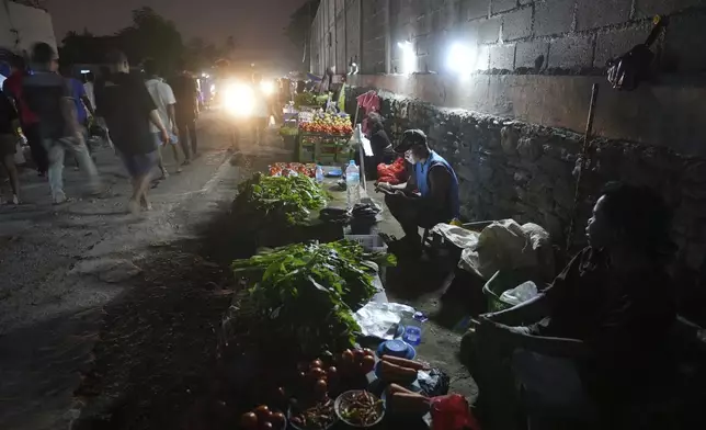 Vendors sell vegetables with battery supported lights at a market in Dili, East Timor Sunday, Sept. 8, 2024. (AP Photo/Firdia Lisnawati)