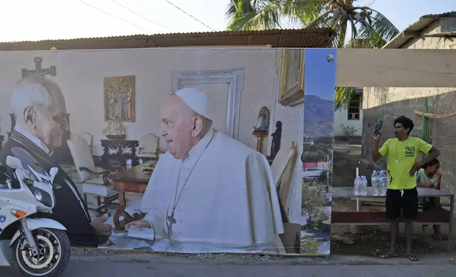 A man stands near a banner showing East Timor's President Jose Ramos-Horta, left, shaking hands with Pope Francis, ahead of the pope's visit to the country, in Dili, Saturday, Sept. 7, 2024. (AP Photo/Dita Alangkara)