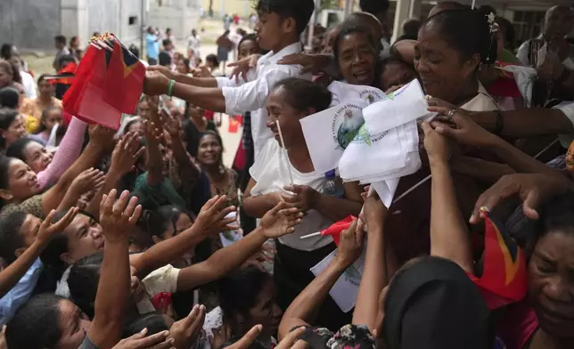 Church officials distribute East Timorese flags and those with a portrait of Pope Francis, after a Sunday Mass ahead of the pope's visit to East Timor, in Dili, Sunday, Sept. 8, 2024. (AP Photo/Dita Alangkara)