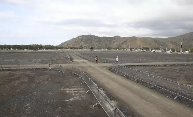 People walk past Tasitolu, an open field on the coast which will be the venue of a papal Mass, in Dili, East Timor, Thursday, Sept. 5, 2024. (AP Photo/Firdia Lisnawati)