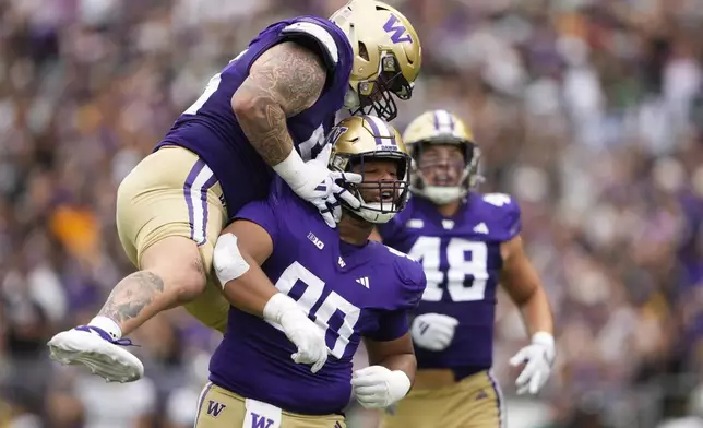 Washington defensive lineman Elinneus Davis (90) is greeted by defensive lineman Jacob Bandes, left, after making a sack against Eastern Michigan during the first half of an NCAA college football game Saturday, Sept. 7, 2024, in Seattle. (AP Photo/Lindsey Wasson)