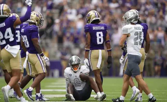 Eastern Michigan wide receiver Markus Allen (8) looks up as the Washington defense celebrates a tackle, including safety Cameron Broussard (8) and safety Makell Esteen (24) during the second half of an NCAA college football game Saturday, Sept. 7, 2024, in Seattle. Washington won 30-9. (AP Photo/Lindsey Wasson)